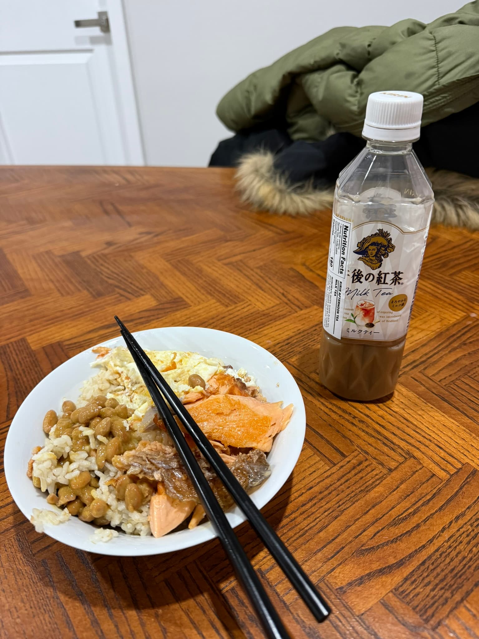 A home-cooked rice bowl and milk tea on a wooden table.